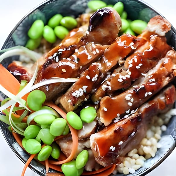 Teriyaki chicken with sesame seeds, edamame, and shredded carrots in a bowl from Sushi Koo.