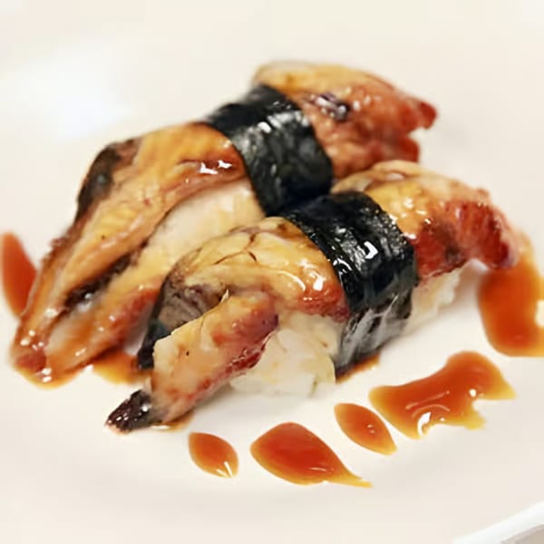 Two pieces of unagi nigiri sushi with dark sauce drizzled on a white plate.