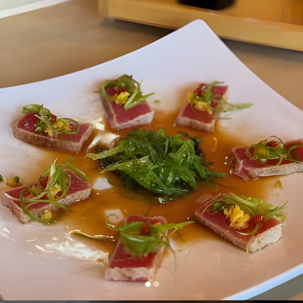 Seared tuna sashimi with seaweed salad and sauce on a white square plate at Sushi Koo.
